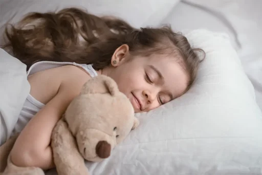 A cute toddler in bed sleeping with teddy
